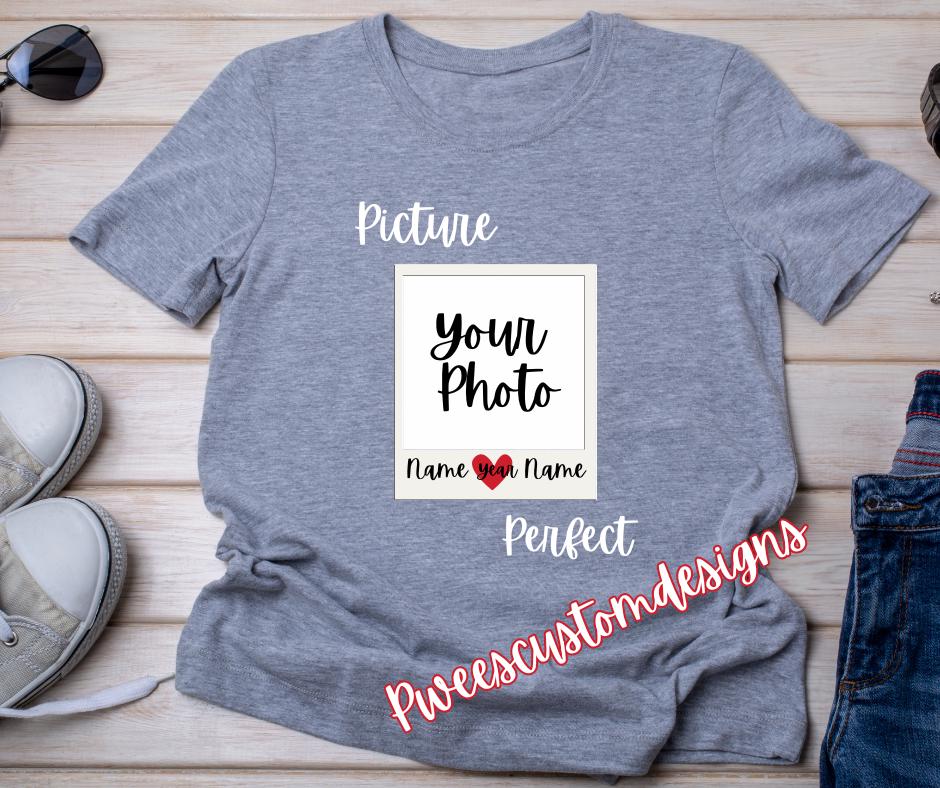 Gray t-shirt with customizable photo and name text on a wooden surface with shoes and jeans.